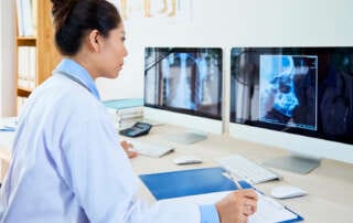 Radiologista analisando exames no monitor através de um software com auxílio de IA